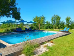 a pool with chairs and umbrellas in a yard at Escale Zen en Quercy in Montalzat