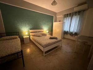 a bedroom with two beds and a green wall at B&B SICILIA in Messina