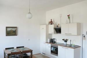 a kitchen with white cabinets and a small table at Apartment Hans - Wohnen im Herzen des Drautales in Feistritz an der Drau
