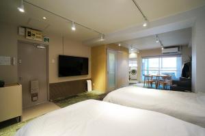 a hotel room with two beds and a flat screen tv at Hotel Sakura Riverside in Nagoya