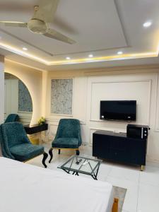 a living room with two chairs and a flat screen tv at Regency Crown Hotel in Faisalabad