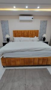 a bedroom with a large bed with a wooden headboard at Regency Crown Hotel in Faisalabad