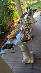 a long table with many plates of food on it at Pousada Éden Rio in Ilhéus