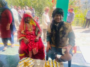 a man and a woman standing next to a table with cakes at Hotel tridev in Manāli