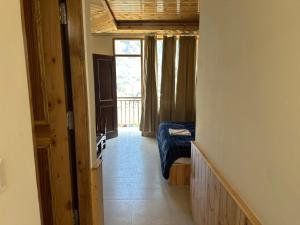 a hallway of a room with a bed and a window at Hotel tridev in Manāli