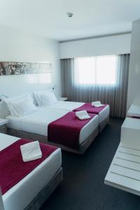 a hotel room with two beds with red sheets at Hotel Costa Verde in Póvoa de Varzim