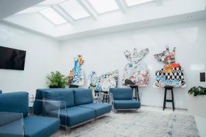 a waiting room with blue chairs and paintings on the wall at Hotel Costa Verde in Póvoa de Varzim