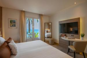 a hotel room with a bed and a desk and a television at Best Western Premier Hotel Prince de Galles in Menton +46 photos