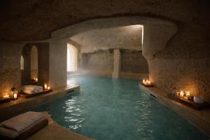 a swimming pool in a cave with candles in the water at GH Masseria Monet in Monopoli