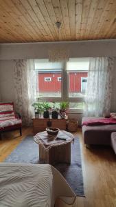 a living room with a bed and a table and two windows at Mumrila in Pori