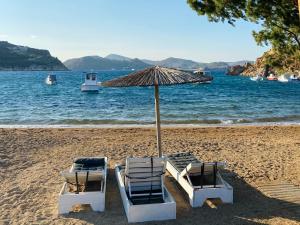 two chairs and an umbrella on a beach at Agnanti Beach House in Patmos