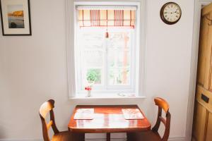 a dining room table with two chairs and a window at bluebird cottage in Angaston