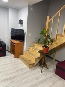 a living room with a wooden staircase with a potted plant at departamento central in Valdivia