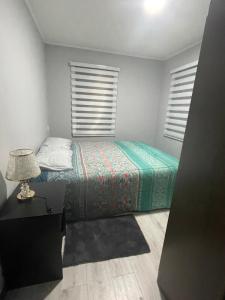 a bedroom with a bed and a lamp and two windows at departamento central in Valdivia