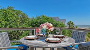 a table with a vase of flowers and wine glasses at 338 Surfsong in Kiawah Island