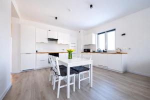 a white kitchen with a white table and chairs at Modern 2023 apartment in Kutno