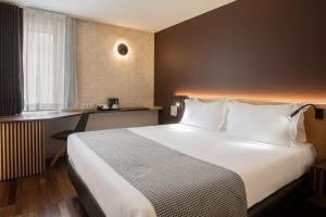 a hotel room with a large white bed and a desk at HF Fénix Urban in Lisbon