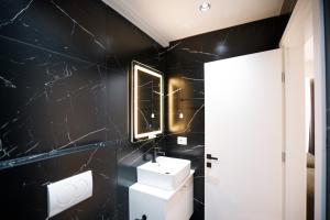 a black bathroom with a sink and a mirror at Silver Stone Studio Apartments in Gjirokastër