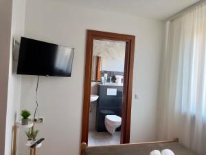 a bathroom with a toilet and a television on a wall at Pension Francesco in Nuremberg