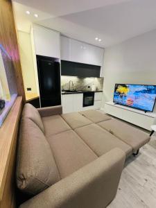a living room with a couch and a flat screen tv at Potka Apartments Tirane in Yzberishti