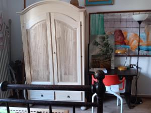 ein Holzschrank in einem Zimmer mit einem roten Stuhl in der Unterkunft Villinolapieve in Castelfiorentino + 2 Fotos