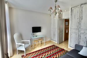 a living room with a table and chairs and a television at Studio de Rêves -SV245- Centre Vincennes in Vincennes