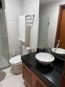 a bathroom with a white toilet and a sink at Apartamento em Resort para família in Barra de São Miguel