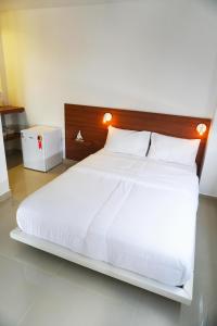 a bedroom with a white bed with a wooden headboard at oceanic suítes in Araruama