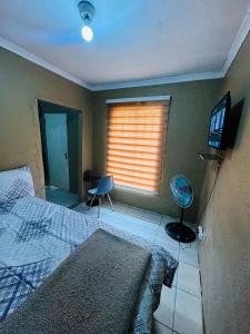a bedroom with a bed and a window with a television at Tseleng Guest House in Vosloorus +18 photos