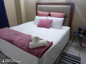 a bed with a teddy bear in a towel at The Glen House in Durban