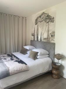 a bedroom with a large bed with white sheets at L'Escale d'Omaha - Cottage de 50m2 in Saint-Marcouf