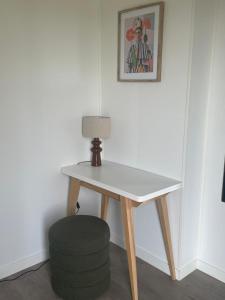 a table with a lamp and a stool in a room at L'Escale d'Omaha - Cottage de 50m2 in Saint-Marcouf