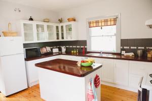 a kitchen with white cabinets and a bowl of fruit on a counter at bluebird cottage in Angaston