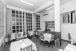 a restaurant with tables and chairs and large windows at Vila Joya Boutique Hotel STP in São Tomé