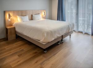 a large bed in a bedroom with a wooden floor at Tulip Inn Honfleur Residence & Spa in Honfleur +87 photos