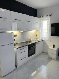 a kitchen with white cabinets and a white refrigerator at Mediterranean Port Suite in Ágios Rókkos
