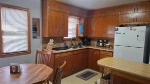 a kitchen with wooden cabinets and a table and a refrigerator at Gano Street Retreat in Great Bend