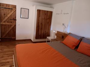 a bedroom with an orange bed and a wooden door at Escale Zen en Quercy in Montalzat