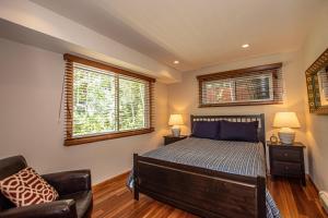 a bedroom with a bed and a chair and two windows at Coates By Hauserman Rentals in Tahoe City