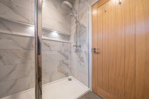 a bathroom with a shower with a glass door at Park Lodge in Penrith +18 photos