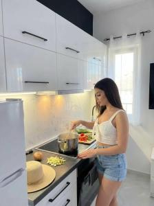 a woman standing in a kitchen preparing food at Mediterranean Port Suite in Ágios Rókkos +9 photos