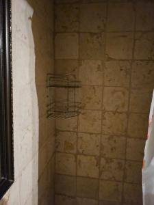 a shower with a tiled wall and a shelf at בית האומן in Safed