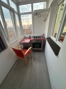 a kitchen with a stove and a chair and windows at Coso in Filiaşi