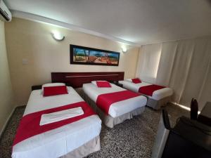 a hotel room with three beds and a tv at Hotel arimaca in Ríohacha