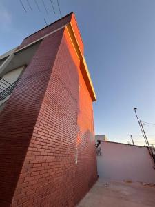 a red brick building with a shadow on the side of it at Loft Novo, Duplex, bem ventilado in Aparecida de Goiânia