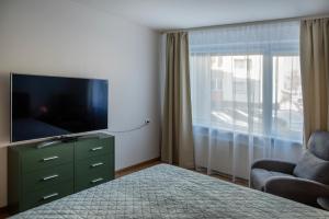 a bedroom with a television and a chair and a dresser at Naftininku in Mažeikiai +9 photos