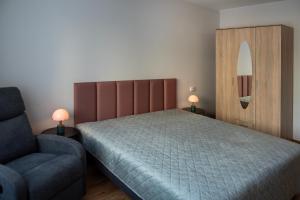 a bedroom with a bed and a chair and a mirror at Naftininku in Mažeikiai