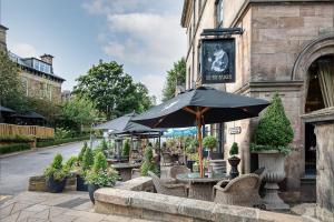 a table with an umbrella in front of a building at White Hart Hotel & Apartments in Harrogate