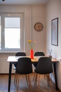 a dining room table with chairs and a vase with flowers at Naftininku in Mažeikiai
