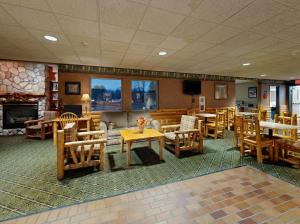 a restaurant with wooden chairs and tables and a fireplace at Pellston Lodge in Pellston